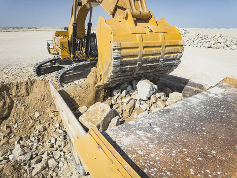 Santa Lucia de Gordon, Spain: View of a large yellow excavator parked in a quarry under a clear blue sky.