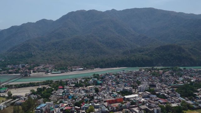Aerial view of dense houses in rishikesh with ganga river and mountains