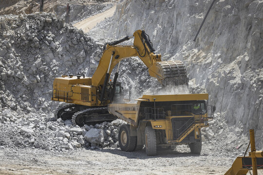 Santa Lucia de Gordon, Spain: View of a large yellow excavator parked in a quarry under a clear blue sky.