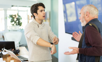 Fototapeta premium Upset senior man employee of company quits job, and guy manager shouts after him..Toxic relationships and abuse of office, unecological environment in team