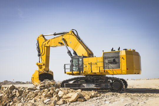 Santa Lucia de Gordon, Spain: View of a large yellow excavator parked in a quarry under a clear blue sky.
