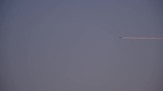 High Altitude Aircraft Leaving Vapor Trail in Sky. Airplane Crossing Blue Sky with Long White Trail. Jet Stream Trail Behind Airplane in Clear Sky. Minimal Sky Scene Plane and Contrail Motion. 