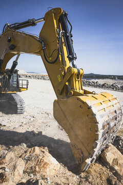 Santa Lucia de Gordon, Spain: View of a large yellow excavator parked in a quarry under a clear blue sky.
