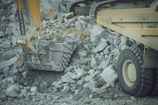 Santa Lucia de Gordon, Spain: View of a large yellow excavator loading grey rocks into a massive dump truck in an open-pit mine.