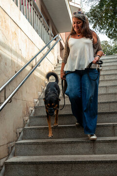 Woman walking down urban stairs with leashed dog