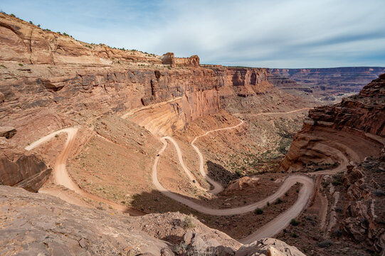 Shafer Trail switchbacks descending Shafer Canyon in Canyonlands National Park, Utah under dense springtime cloudscape..