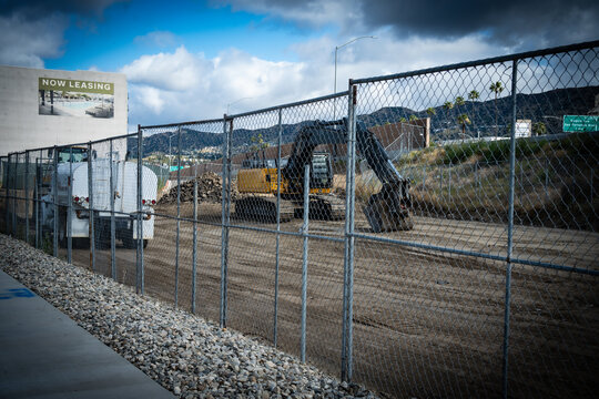 Construction site with heavy machinery and a "Now Leasing" sign visible