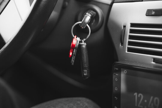 Keys with a plastic red key fob stick out in the ignition lock of the car. symbolic abstract photo. High quality photo