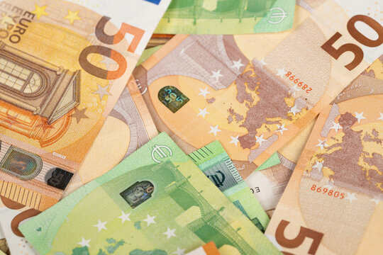 Closeup fifty and hundred euro banknotes highlighting holograms, microprint and reflective foil, crisp texture and color contrast for anticounterfeit and editorial finance use