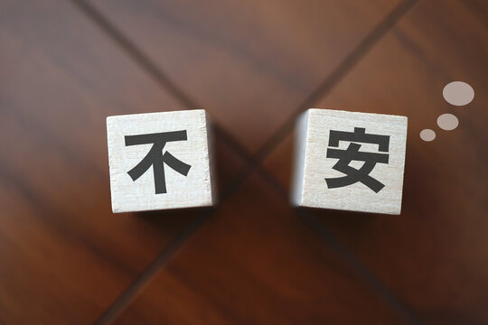 不安とストレスのイメージ。不安と書かれた漢字ブロック。茶色背景