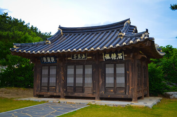 Obraz premium Traditional Korean wooden pavilion with tiled roof in park setting. Cultural architecture and heritage concept.