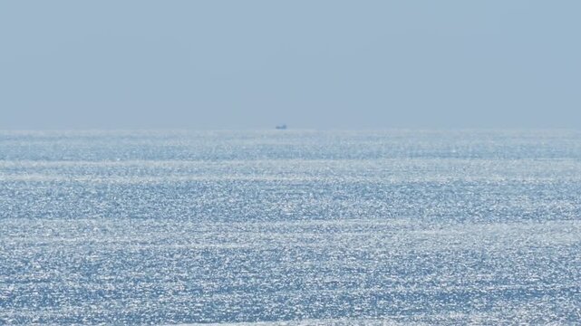 Heat haze over the glittering ocean surface with birds flying in the distance.