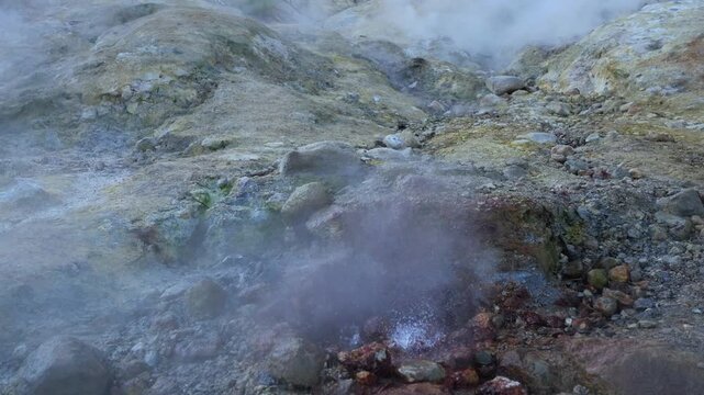 Geothermal springs with bubbling hot water and colorful mineral deposits, steam rising from rocky terrain, showing geothermal activity, vibrant colors and dynamic movement. Close up