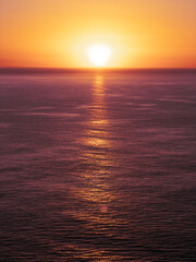 Obraz premium Sunrise over the ocean in purple and orange tones with copy space