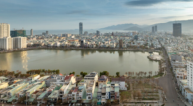 Aerial view of Sinh Thai Lake, Quy Nhon, Binh Dinh, Vietnam, at sunset. The sun reflects on the lake, with mountains in the background.