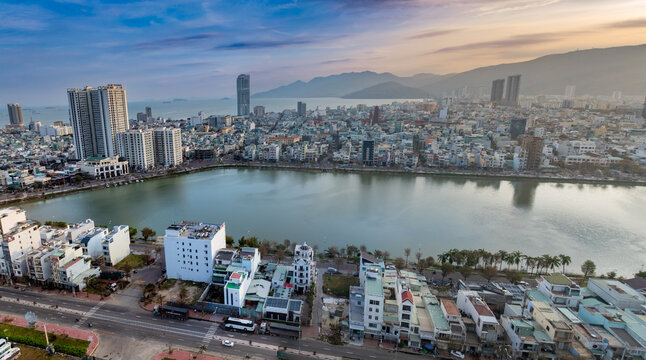 Aerial view of Sinh Thai Lake, Quy Nhon, Binh Dinh, Vietnam, at sunset. The sun reflects on the lake, with mountains in the background.