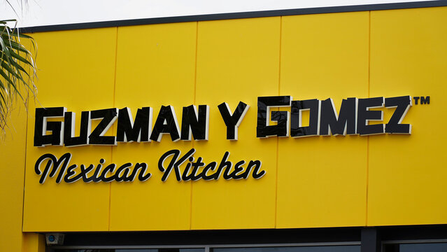 Guzman y Gomez Mexican Kitchen sign on a bright yellow building in a busy area during daytime hours