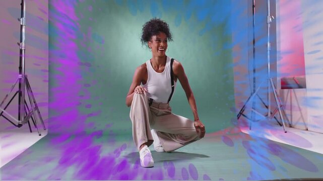 Woman crouching moving hands sparking expanding paint ring around her over green backdrop for promo