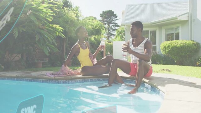 Man and woman sitting poolside, toasting and chatting while midway tech overlays floating over pool