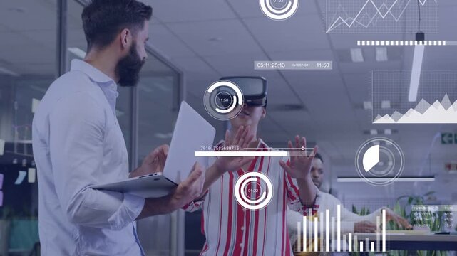 VR tester woman testing UI, holding forward, expanding charts while colleague checking laptop