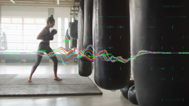 Female fitness trainee striking heavy bags in gym, waveform pulsing with each hit tracking power
