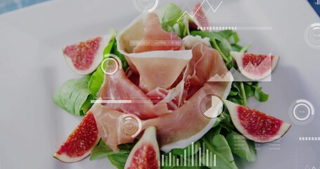 Fototapeta premium Showing prosciutto rosette resting on greens on white plate on tabletop, with figs and HUD overlays
