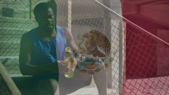 Man sitting on bleacher steps reaching for yellow bottle after workout Mexican flag overlay growing
