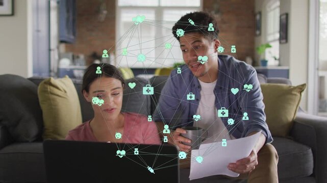 Woman typing on laptop as man leaning in pointing papers sparking teal health network for review