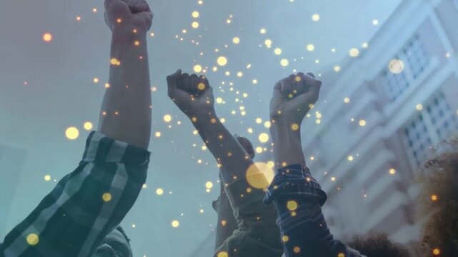 Friends celebrating success in atrium, raising fists while golden bokeh growing for marketing
