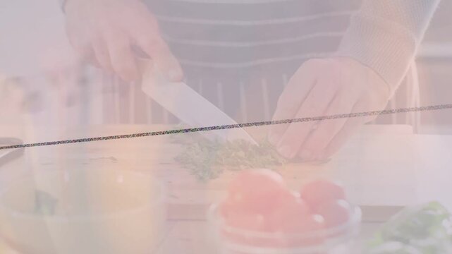 Male cook grasping knife, chopping herbs into mince for meal prep, pink overlay over workspace