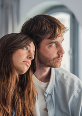 Obraz premium Pensive young couple leaning together in a quiet intimate moment at home, thoughtful and emotional portrait