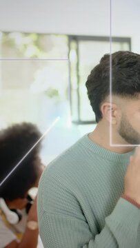 Vertical video: Man in sweater shifting, holding cup, preparing to sip while tech lines framing him
