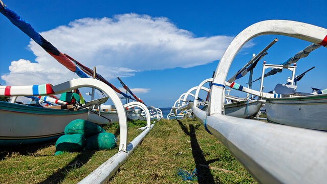 Low Angle View of Traditional Balinese Jukung Fishing Boats with Outriggers on Coastal Grassland in Bali