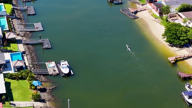Aerial view of rowing scull moving through luxury residential canal at gold coast queensland.