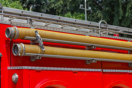 Close-up of yellow suction hoses mounted on the side of a red fire truck.