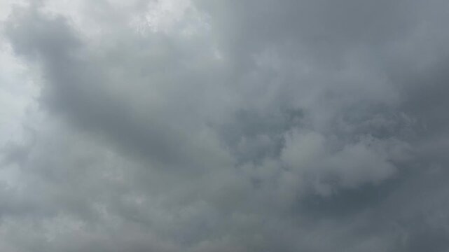Dark, ominous storm clouds gather across a vast, grey sky, signaling an impending change in weather and creating a dramatic, moody atmosphere before a storm