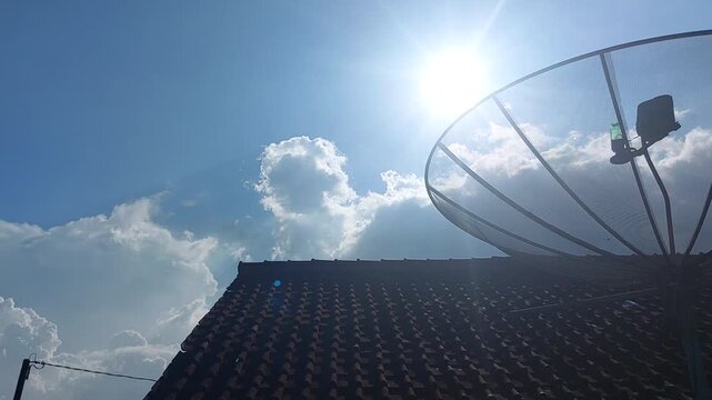A Satellite Dish on a Rooftop Under a Bright, Sunny Sky with Fluffy Clouds