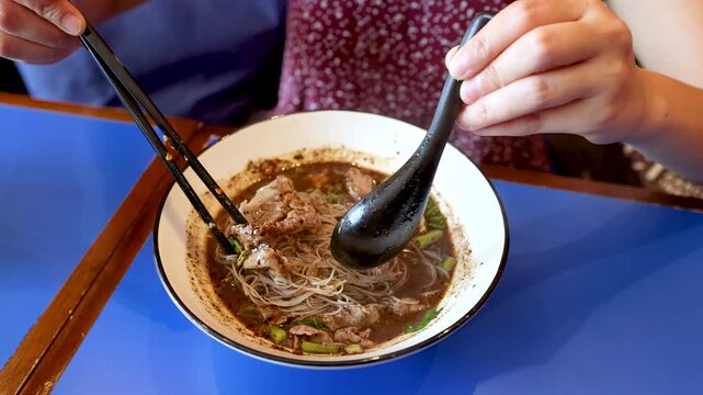 Person Eating Thai Boat Noodles with Pork and Rice Vermicelli
