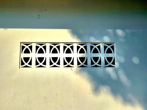 Traditional Concrete Breeze Block Vent on Sunlit White Wall