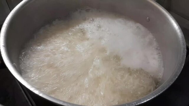 Cooking white Basmati rice video footage isolated background. Rice boiling for meal in a metal pot. 