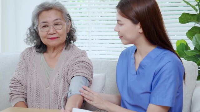 Asian woman nurse measuring blood pressure senior patient, medical checking for hypertension monitoring, caregiver support elderly woman with arterial blood pressure device, routine health checkup.
