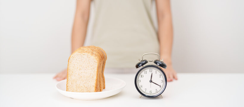 Happy smiling woman with whole wheat bread and alarm clock. concept of intermittent fasting, IF, meal timing, and choosing healthy carbohydrates for a balanced diet and weight loss management