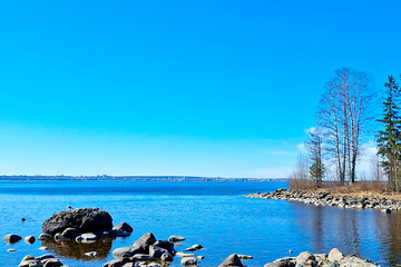 Spring sky-water landscape of the large Onega Lake along the rocky shore. © Ludmila