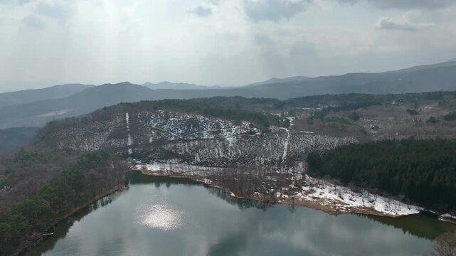 Aerial overview of round-shaped Menuma Pond with surrounding forest, Fukushima Japan