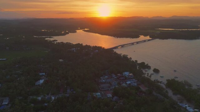 Aerial sunset Cinematic golden hour lush palm tree canopy of General Luna, Siargao. Aerial view of the tropical island landscape and glowing sunset horizon in the Philippines