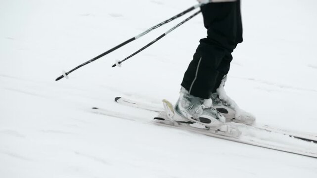 Close up of beginner skier standing on skis learning winter sport practice on snowy slope minimal scene outdoor.