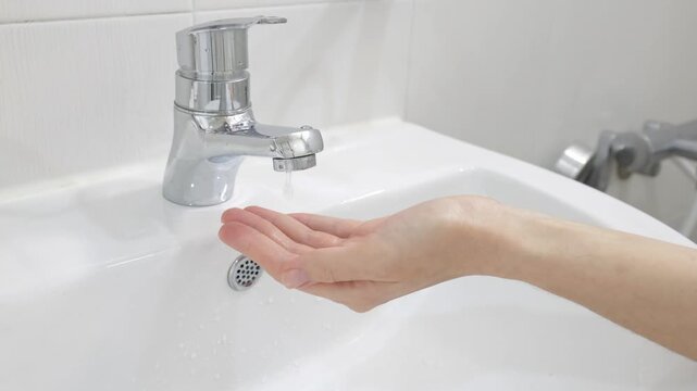 Hand under faucet with little or no water flow, low pressure and water shortage concept, daily life problem and infrastructure issue
