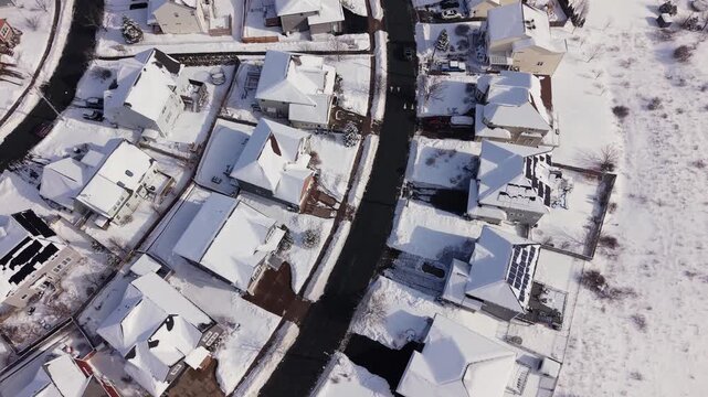 Drone view of snow-blanketed houses and cottages in the lakeside neighborhood of Fairmount, Halifax, Nova Scotia. Canada. Winter snowscape after storm with calm frozen lake 4K.