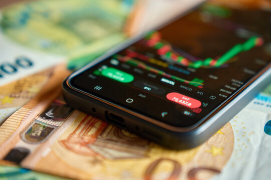 Smartphone showing trading app with market chart on euro banknotes. Concept of online investment, financial risk, mobile trading and digital finance.