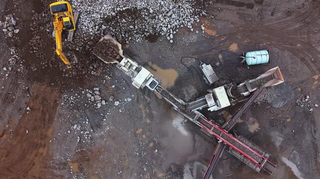 Top View of a large vibrating screen stone crusher in active operation at a quarry near Halifax, Nova Scotia, Canada. Heavy mobile machinery processes limestone and rocks into construction materials